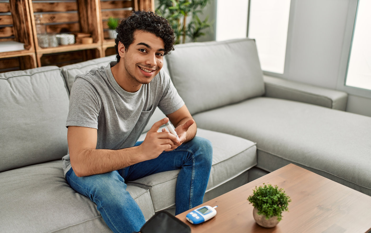 young hispanic diabetic man measuring glucose sitting on the sofa at home